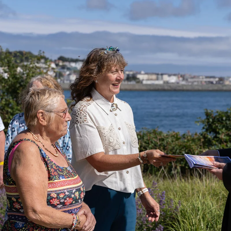Group of people arriving for a remembrance gathering in a coastal setting at Bathing Pools, Guernsey.