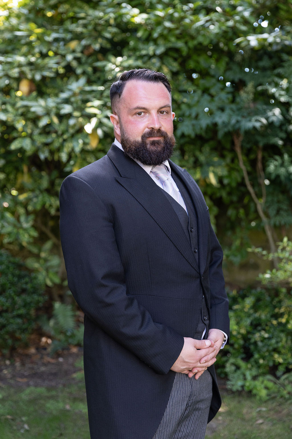 Coop Funeral Care by Argent funeral director standing outdoors with trees and greenery in the background.