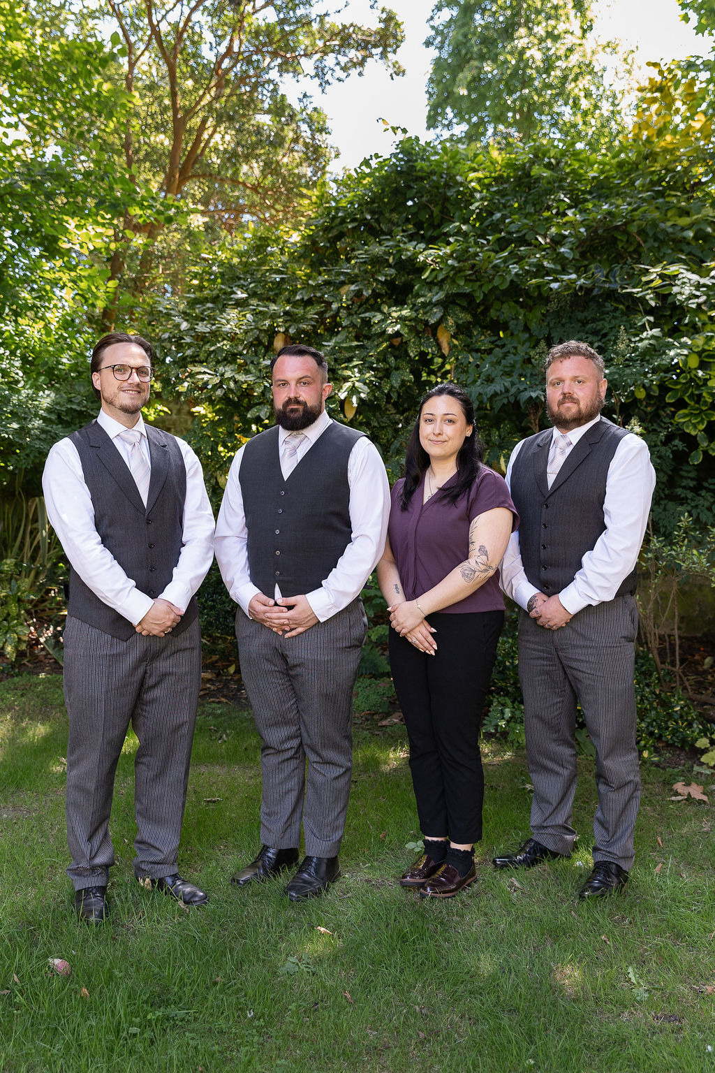 The funeral team standing together in a garden with green bushes behind them.