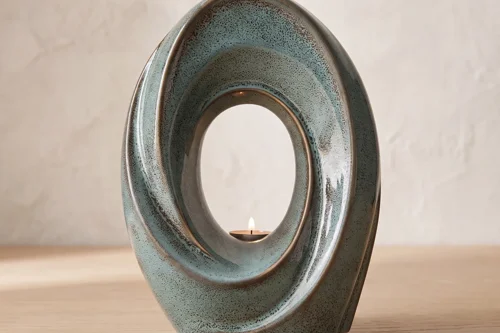 Decorative ceramic memorial candle holder featuring a lit tealight within a sculpted oval frame.