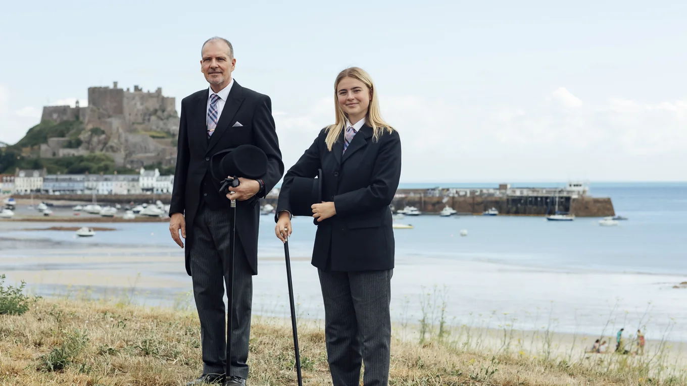 Funeral Directors Standing next to each other with Gorey Castle and harbour in the background.