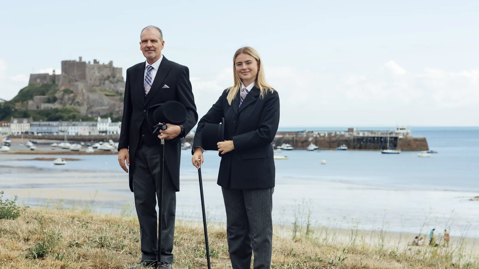 Funeral Directors Standing next to each other with Gorey Castle and harbour in the background.
